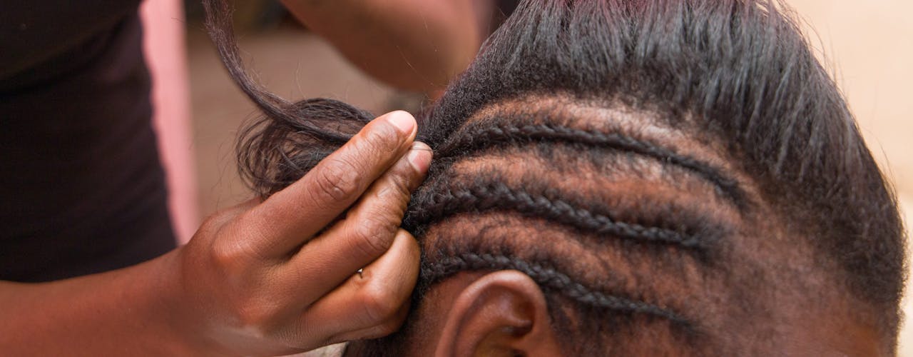 Abigail* braiding a client in her salon