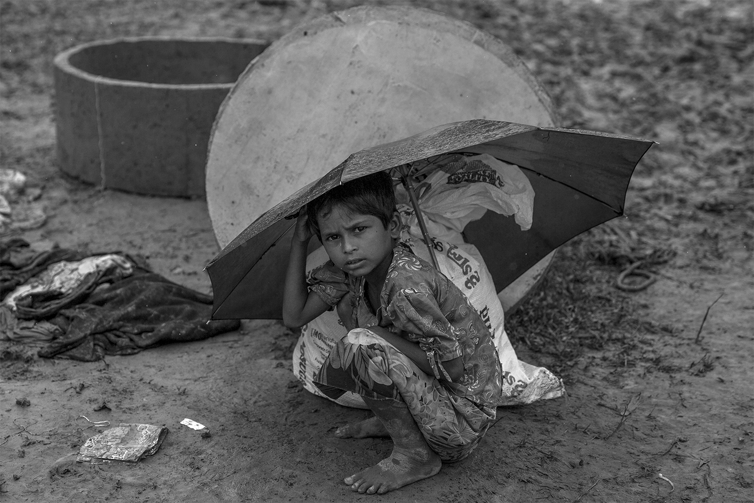 A Rohingya Muslim girl, who crossed over from Myanmar into Bangladesh, waits for her mother as she takes shelter under an umbrella after collecting food aid as it rains in Balukhali refugee camp, Bangladesh, Monday, Sept. 18, 2017. Bangladesh has been overwhelmed with more than 400,000 Rohingya who fled their homes in the last three weeks amid a crisis the U.N. describes as ethnic cleansing. Refugee camps were already beyond capacity and new arrivals were staying in schools or huddling in makeshift settlements with no toilets along roadsides and in open fields.